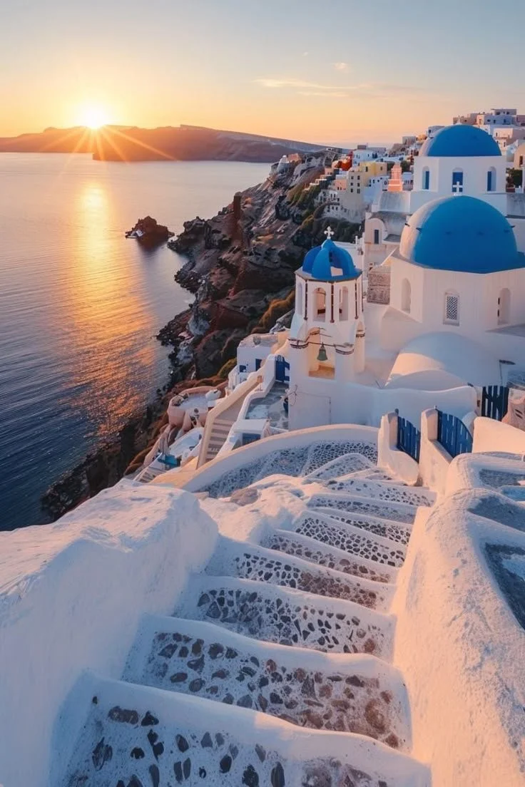 A picturesque sunset view of Santorini with iconic white buildings and blue domes.